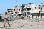Un rebelle avance dans le centre de Syrte, en ruine, samedi dernier.