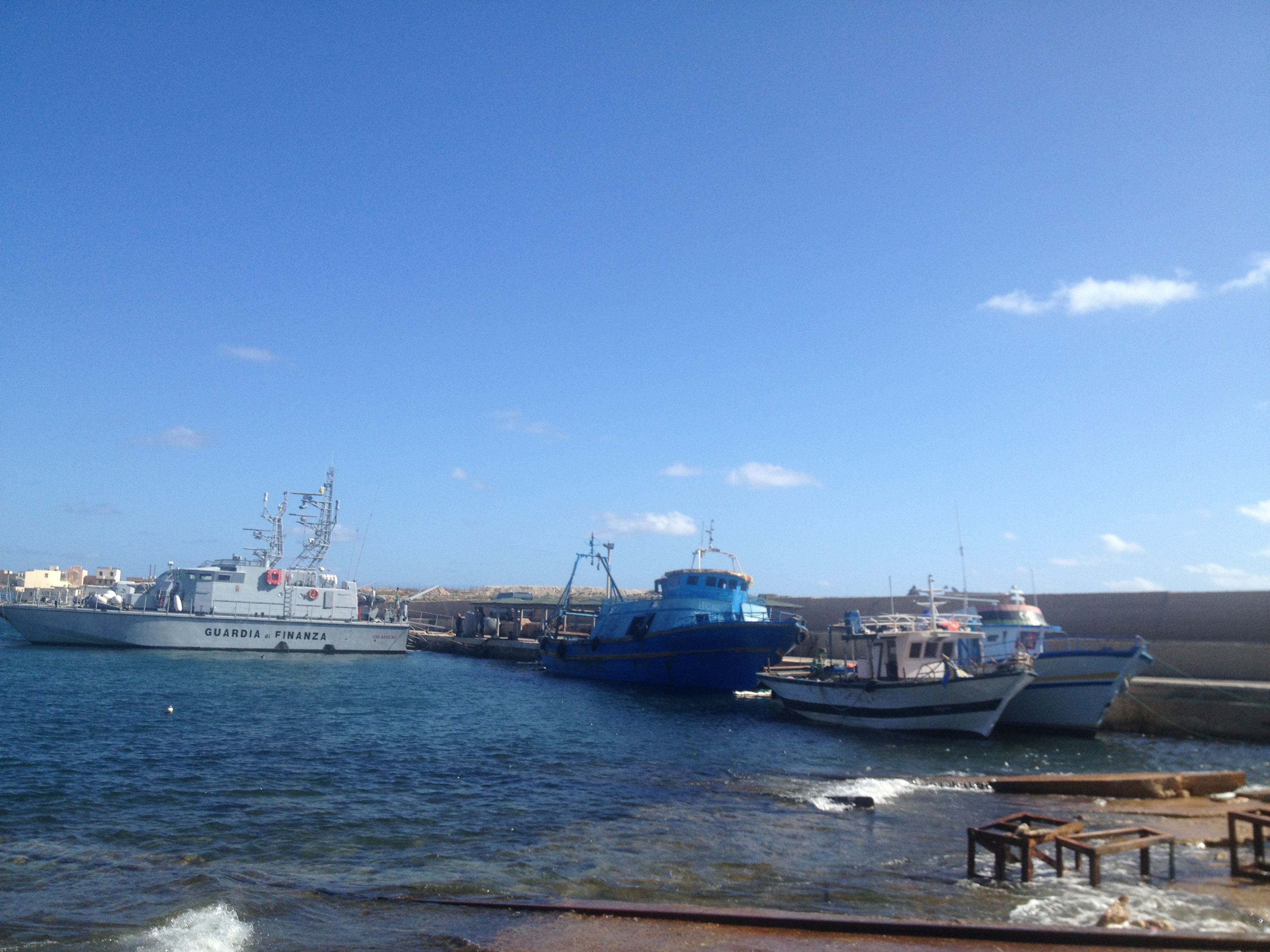 Le port de Lampedusa, le 20 octobre 2013. Trois barcasses de boat-people dans le port de Lampedusa à côté d'une des vedettes des Douanes. La petit barcasse blanche est arrivée de nuit au port sans être repérée, quatre jours après le naufrage du 3 octobre. Elle contenait 200 boat-people. Photo : François Dufour