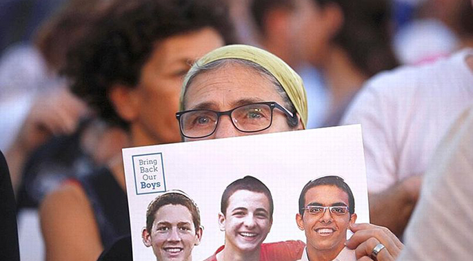 Une femme brandit la photo des trois adolescents assassinés.
