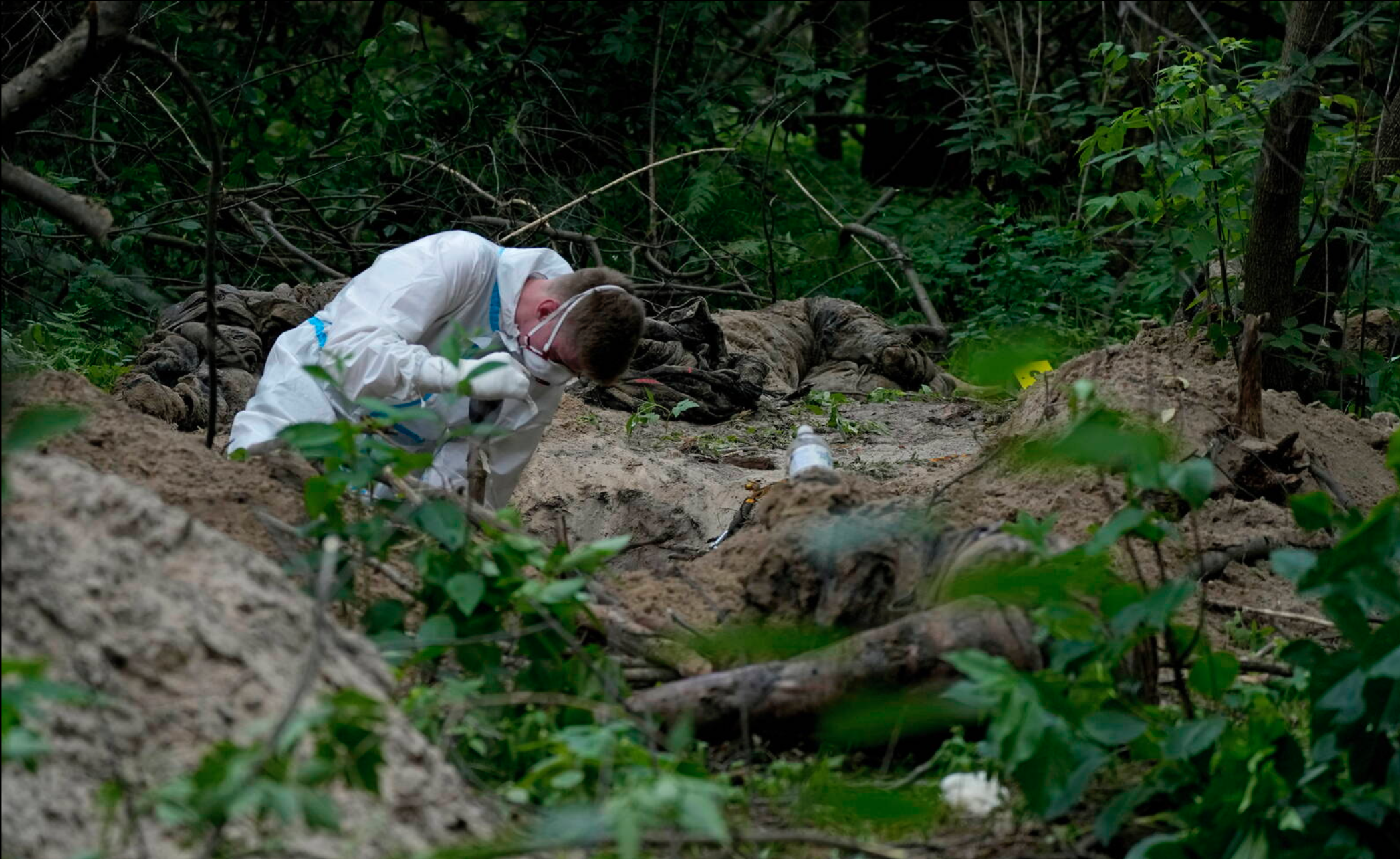 Un membre d'une équipe d'extraction travaille pendant l'exhumation d'un charnier près de Boutcha, dans la banlieue de Kyiv, le 13 juin 2022