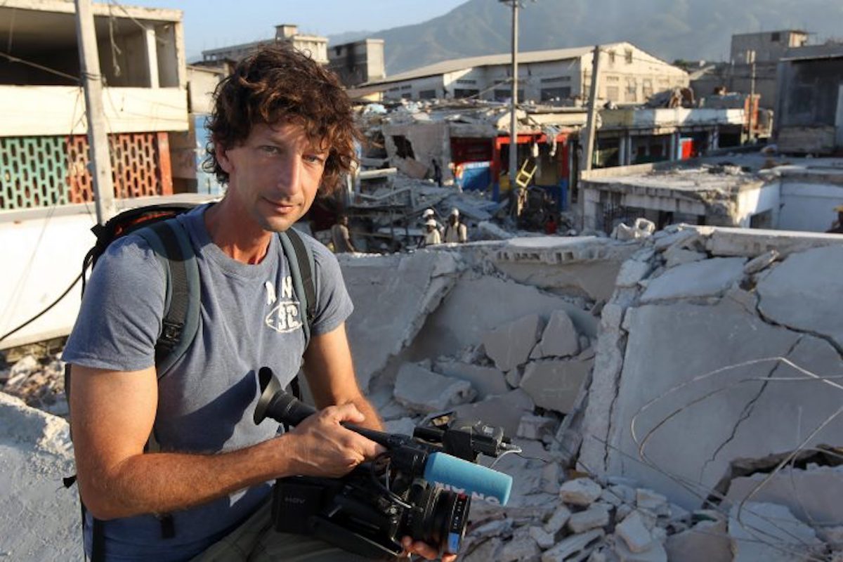 Itai Anghel, le reporter de guerre, avec sa caméra à côté d'un immeuble détruit.