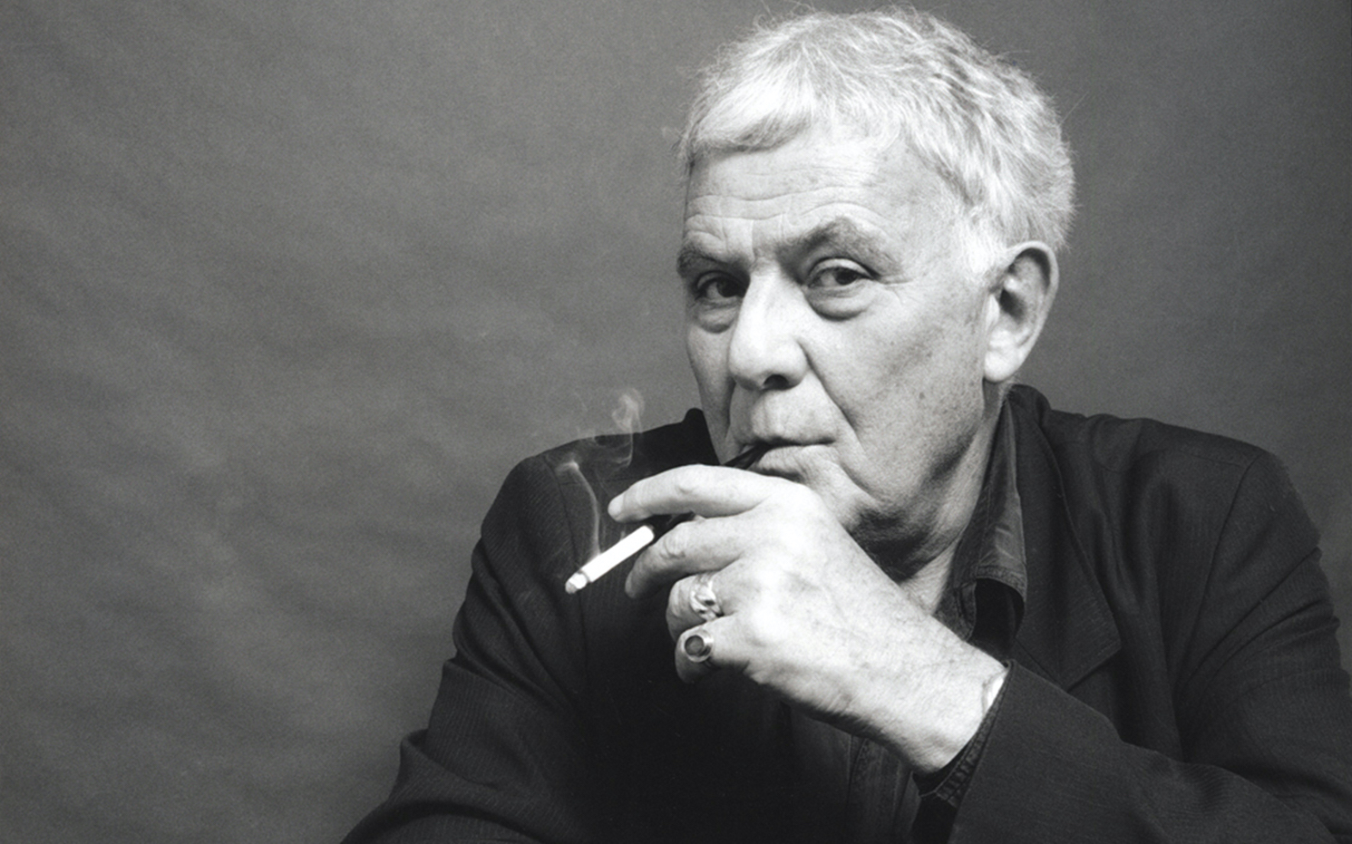 Portrait en noir et blanc de l'écrivain Philippe Sollers e,n train de fumer une cigarette.