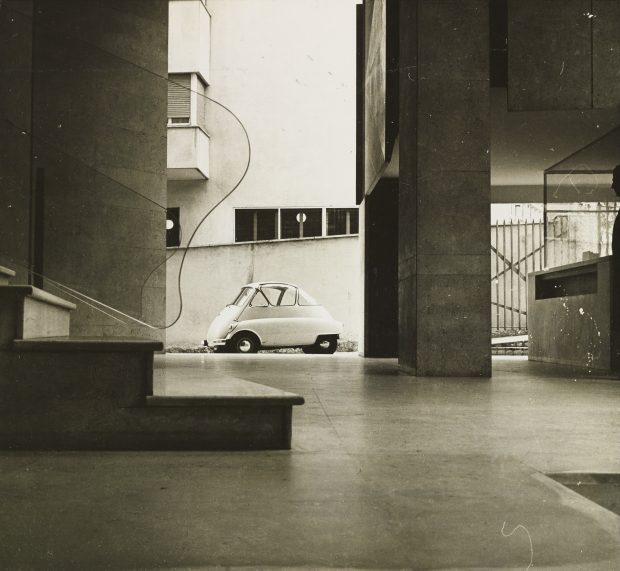 La voiture Isetta garée à côté de l'appartement Moretti aux rampes d'escalier en verre.