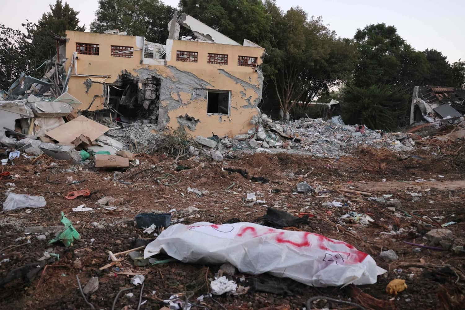 Un corps gît en face d'une maison détruite du kibboutz de Be'eri.