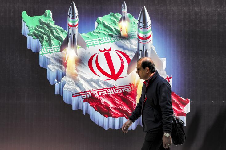 Un homme marche devant la carte de l'Iran dans le centre de Téhéran.