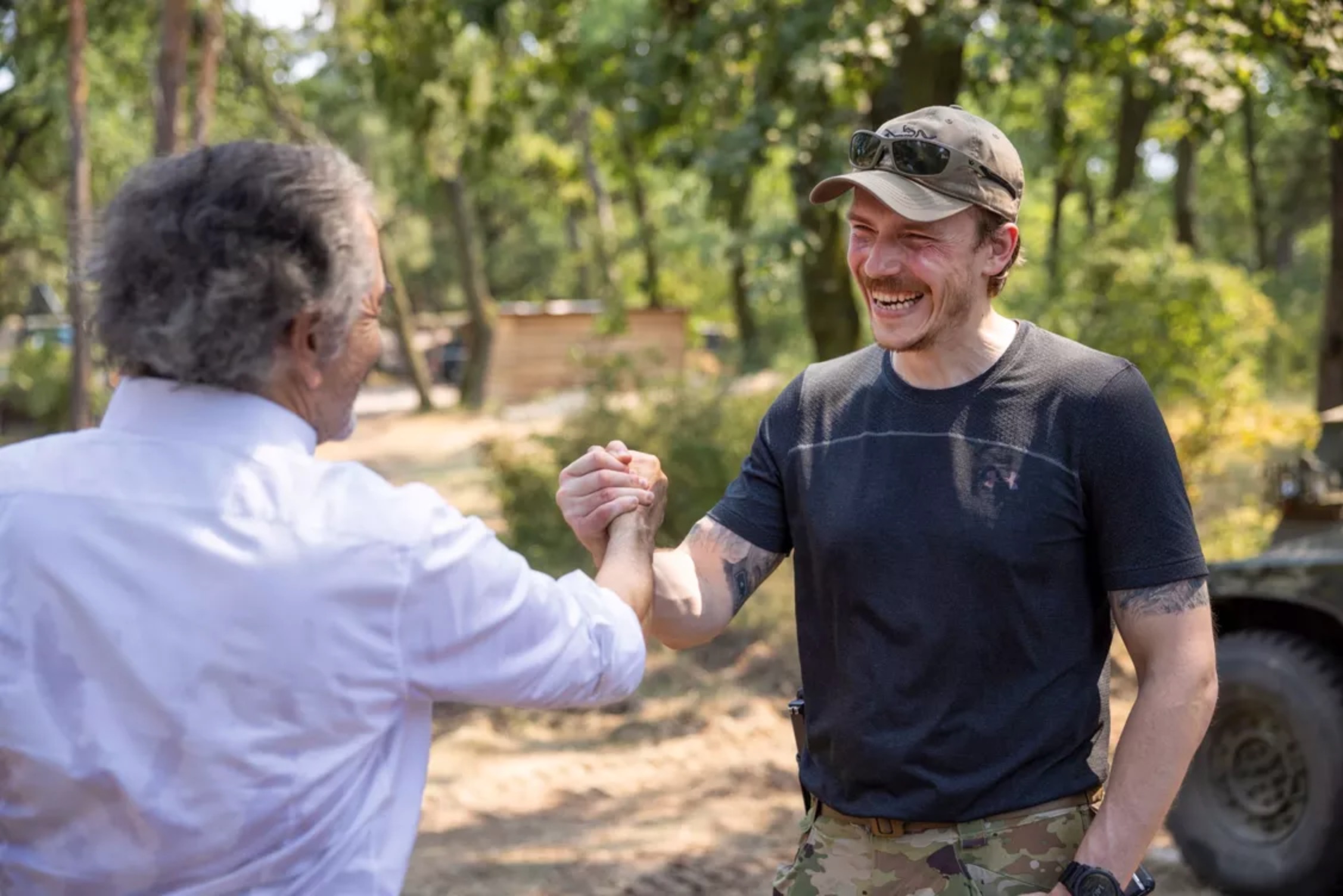 De dos, Bernard-Henri Lévy serre la main de Denys Prokopenko sur le front ukrainien.