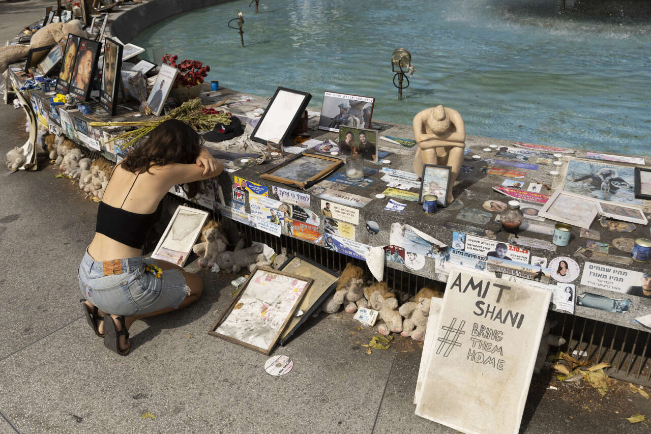 Une femme se recueille, à Tel-Aviv, devant les photos des personnes tuées ou enlevées un an plus tôt lors des attaques du Hamas du 7 octobre 2023.