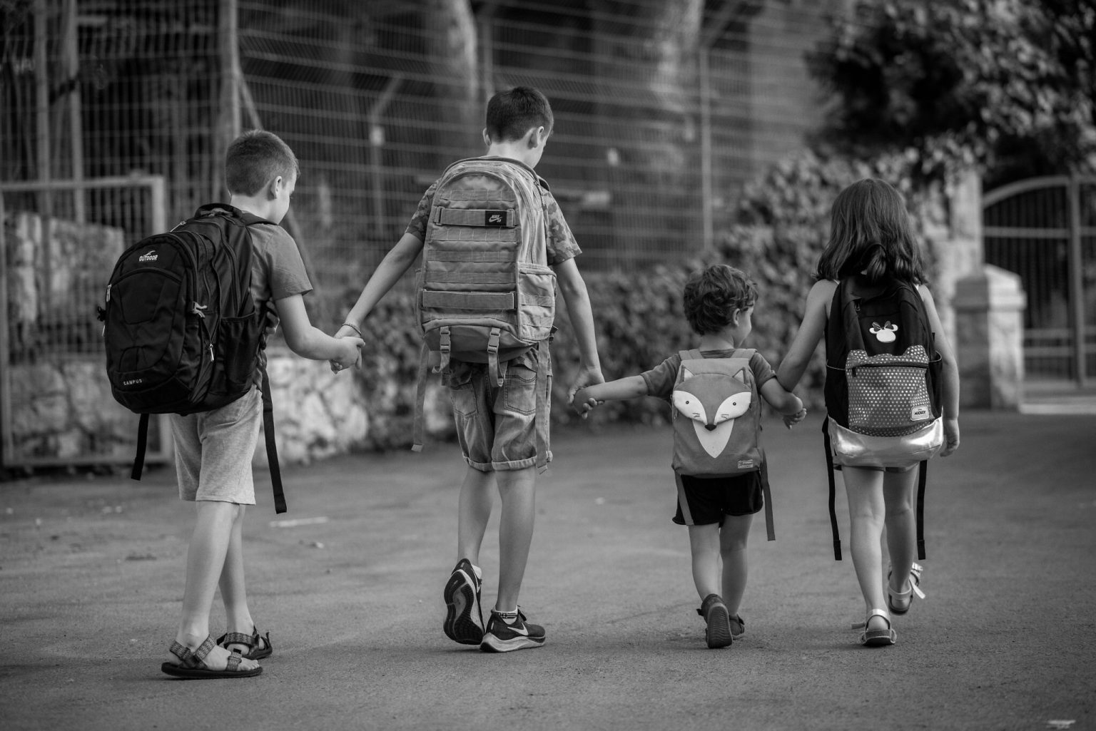 Enfants israéliens à Jérusalem qui se tiennent par la main, de dos, avec des sacs cartable.