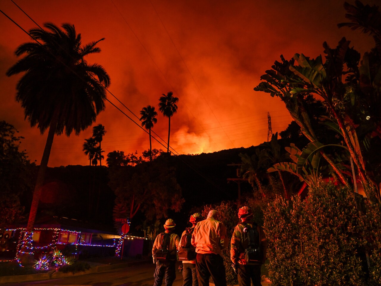 L'incendie de Los Angeles, on voit des pompiers près d'une maison et les flammes à quelques mètres.