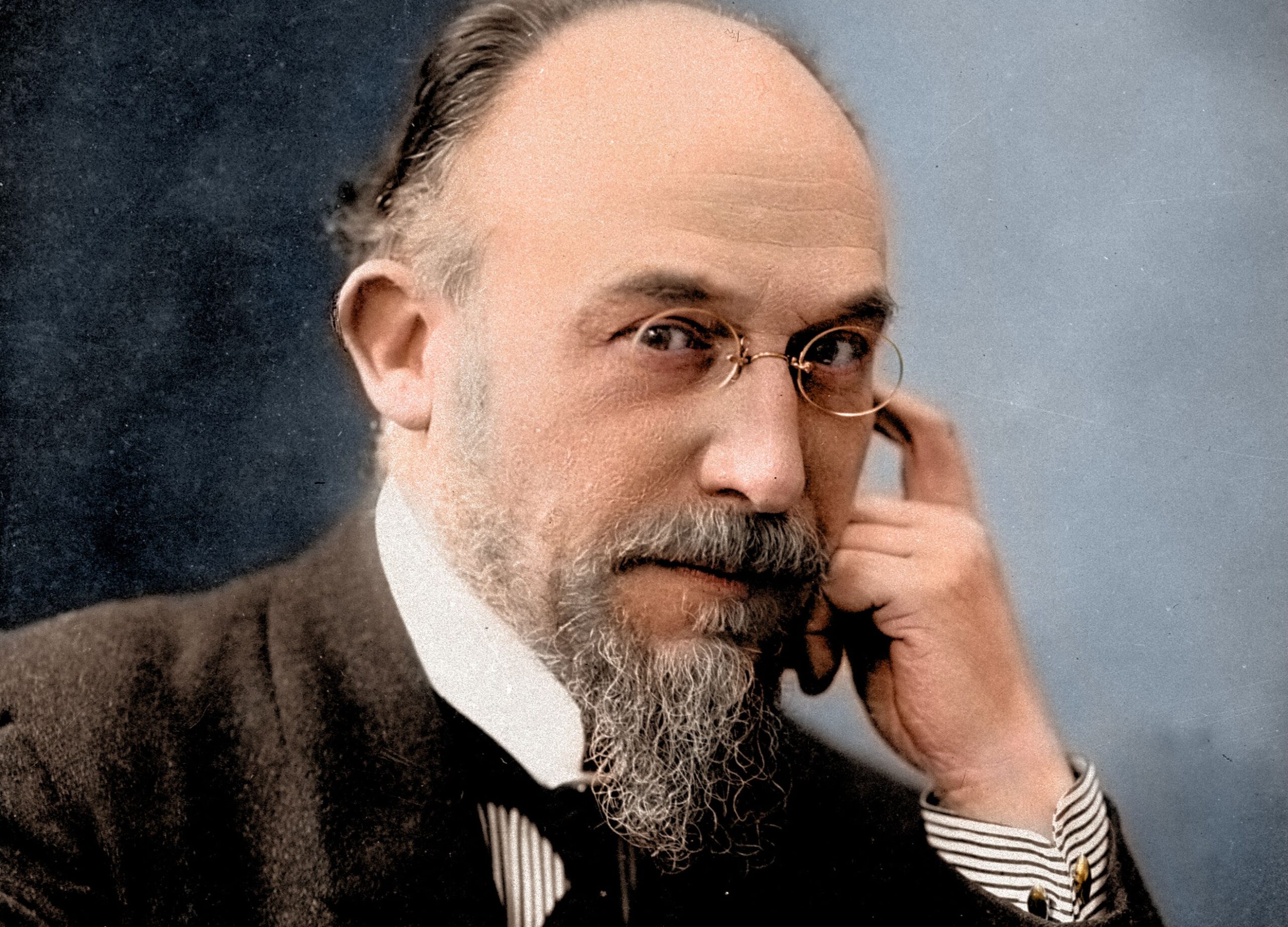 Portrait coloré d'Erik Satie, le grand compositeur. Il est assis face à son bureau.