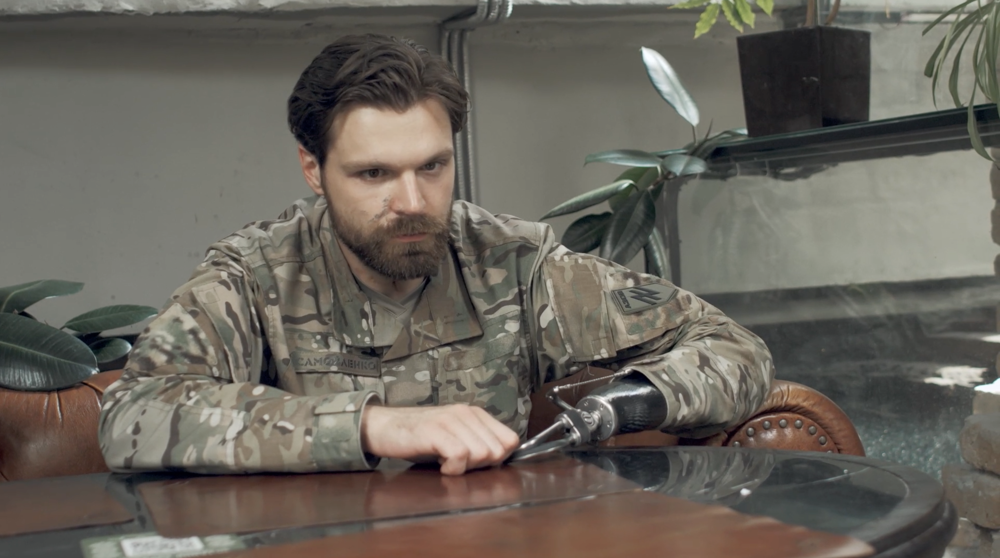 Ilya Samoïlenko, assis derrière un bureau, il porte un treillis militaire, et porte un crochet à la place de sa main amputée.