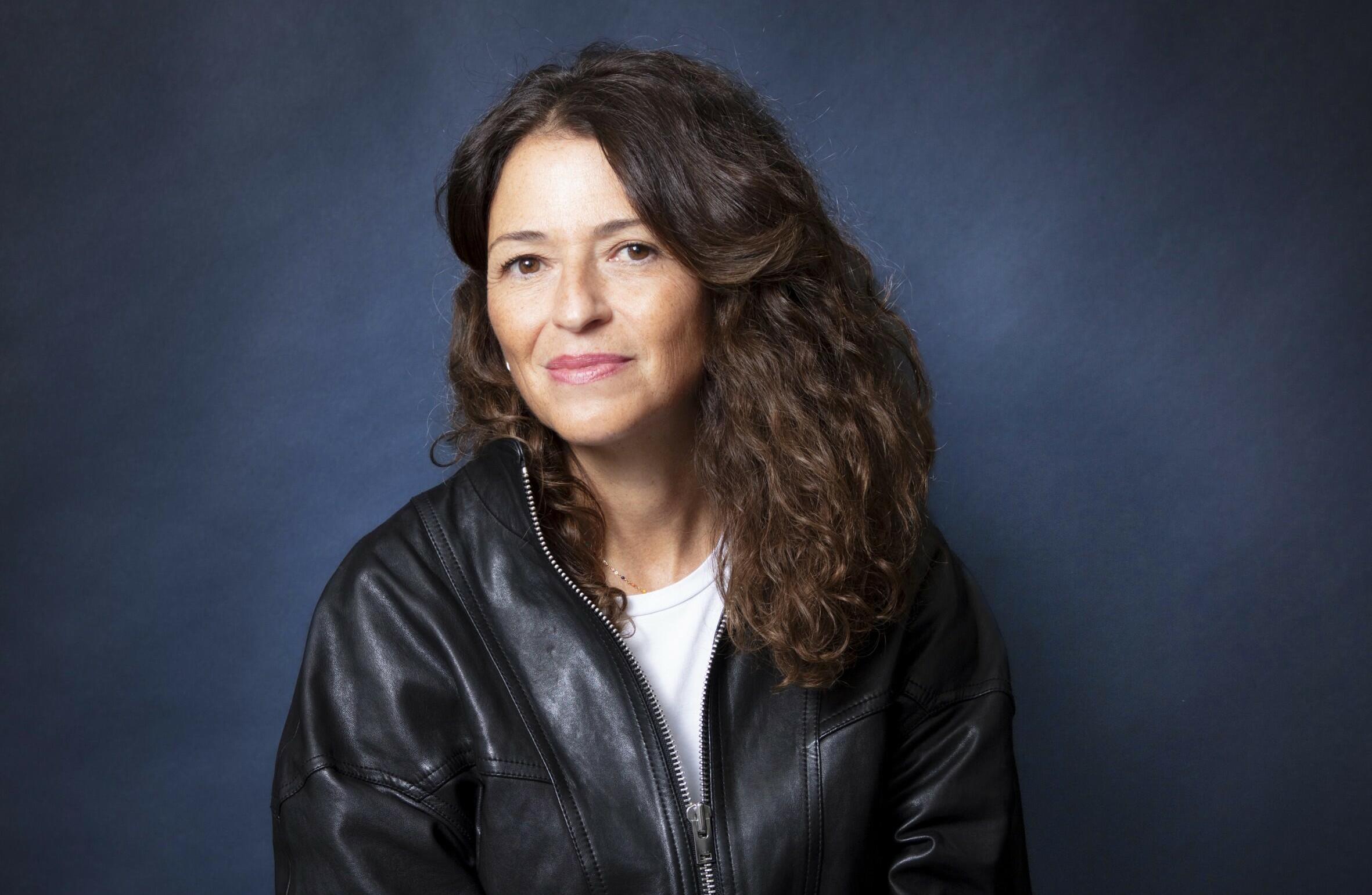 Portrait de Karine Tuil. L'écrivaine porte un t-shirt blanc et un blouson en cuir.