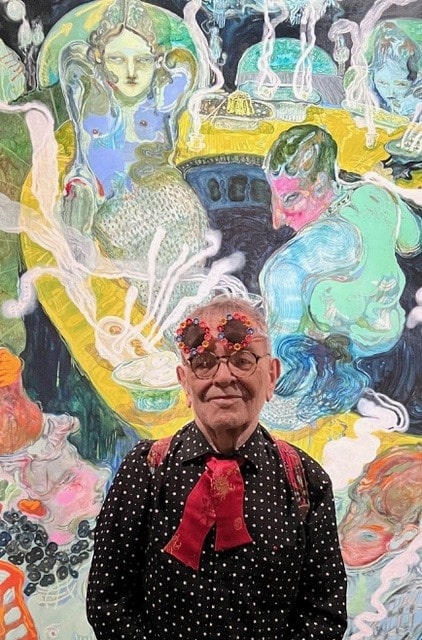 Fernando Arrabal visite l’exposition « Les Sept Sens Célestes » à l’Hôtel de la Marine, il pose devant une peinture colorée.