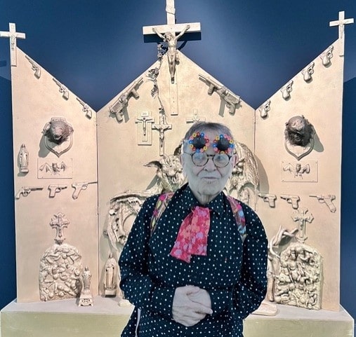 Fernando Arrabal visite l’exposition « Niki de Saint Phalle, Jean Tinguely, Pontus Hulten » au Grand Palais, à Paris. Il pose devant « L’Autel OAS » de Niki de Saint Phalle.