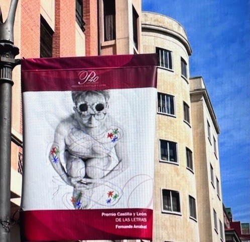 Le Prix Castilla y León des Lettres, qui distingue les contributions exceptionnelles à la culture castillane et léonaise ainsi qu’au savoir universel, a récompensé Fernando Arrabal pour son œuvre en 2023. L'image montre une affiche suspendue en hauteur contre un mur, comportant une photo en noir et blanc d'Arrabal (prise par Juan Barte) annonçant le lauréat du prix.