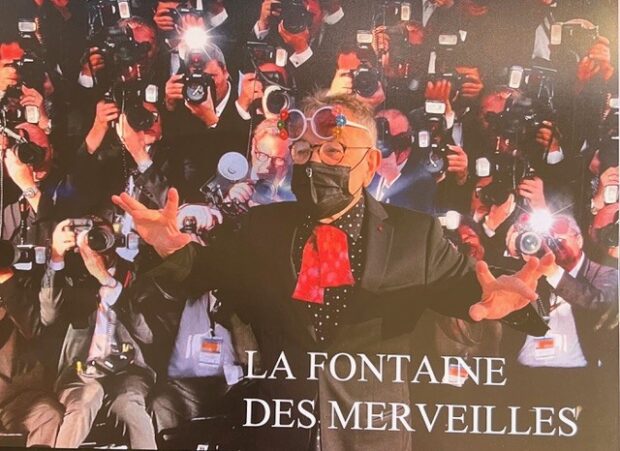 Fernando Arrabal au Festival de Cannes, gravissant le tapis rouge, tandis qu'un mur de photographes derrière lui capture son image avec des flashes.