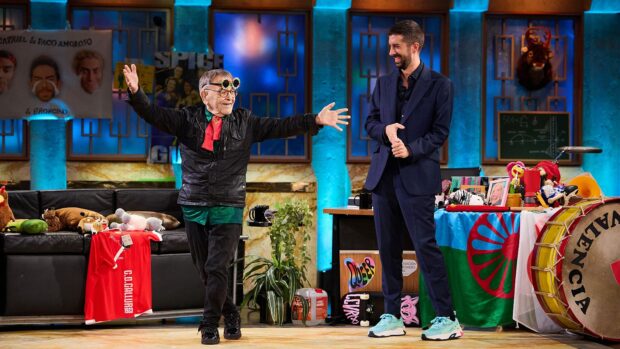 Le poète et dramaturge Fernando Arrabal sur le plateau de l'émission emblématique de la télévision espagnole, La Revuelta, animée par David Broncano. Le décor, un appartement aux couleurs vives, sert de toile de fond tandis qu'Arrabal se tient debout, les bras écartés. A droite, David Broncano est debout.