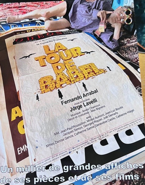 Fernando Arrabal allongé au-dessus d'une affiche de sa pièce « La Tour de Babel », créée par la Comédie-Française au théâtre de l'Odéon en 1979, mise en scène par Jorge Lavelli.