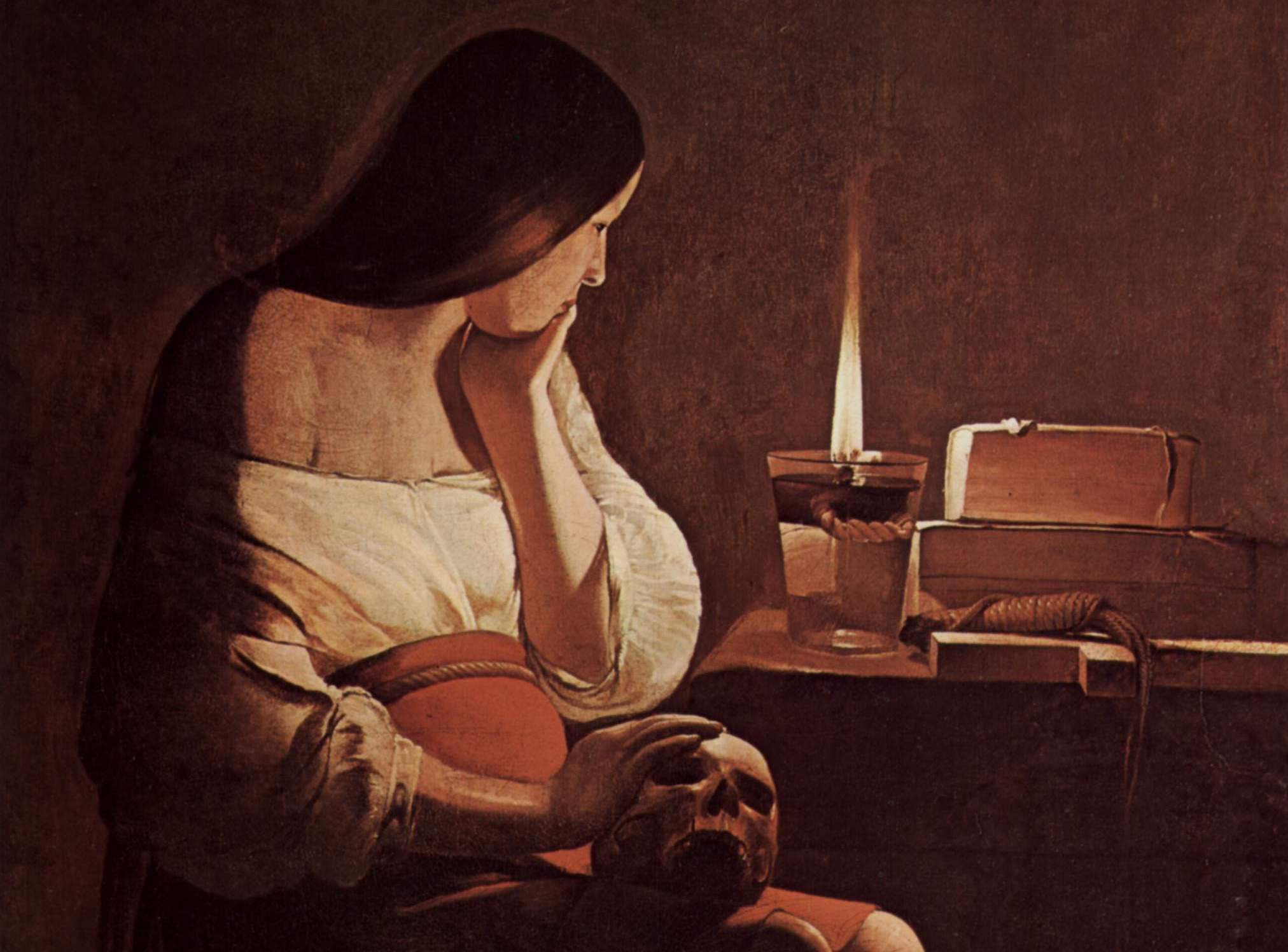 La Madeleine à la veilleuse montre sainte Marie-Madeleine, pieds nus et vêtue d’une simple bure, méditant dans la pénombre. Assise, une main posée sur un crâne posé sur ses genoux, elle contemple la flamme d’une lampe à huile qui l’éclaire.