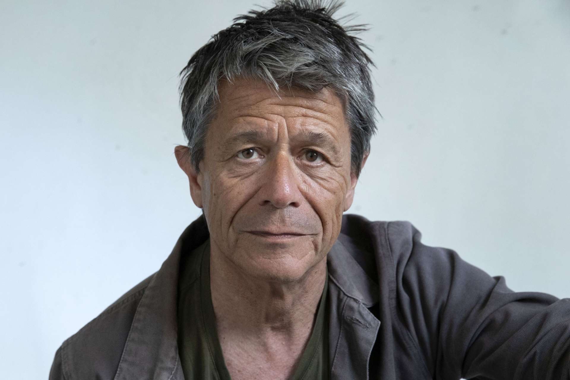 Portrait de l'écrivain Emmanuel Carrère, devant un fond blanc.