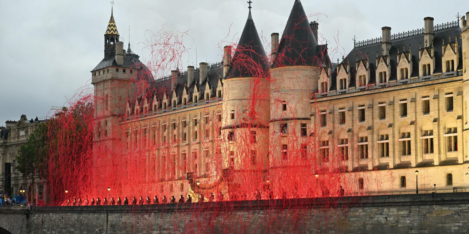 La mise en scène de Thomas Jolly pour les JO 2024 à la Conciergerie : on voit de grands fils rouges projetés sur le quai devant le bâtiment.