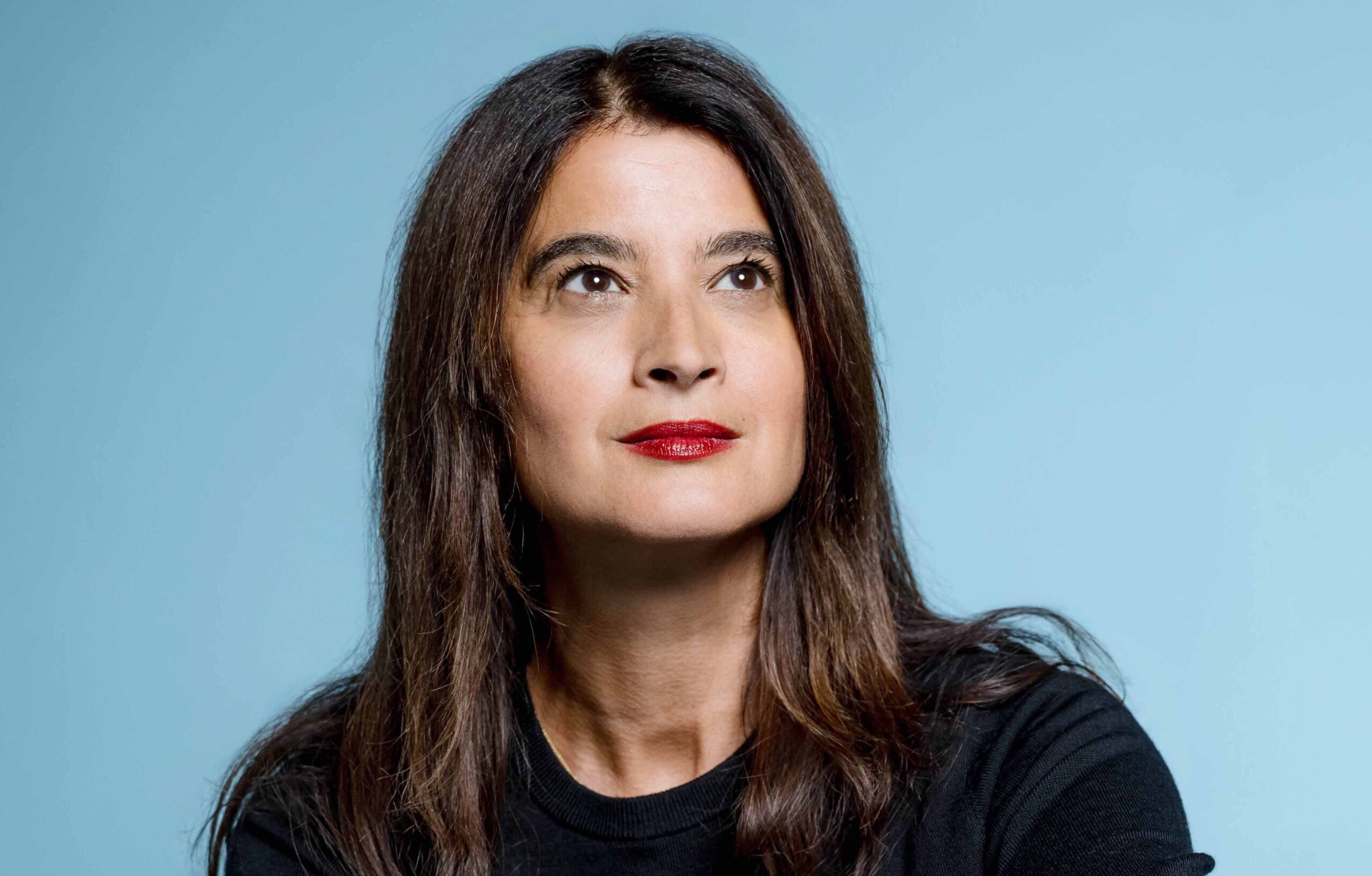 Portrait de Vanessa Schneider devant un fond bleu ciel.