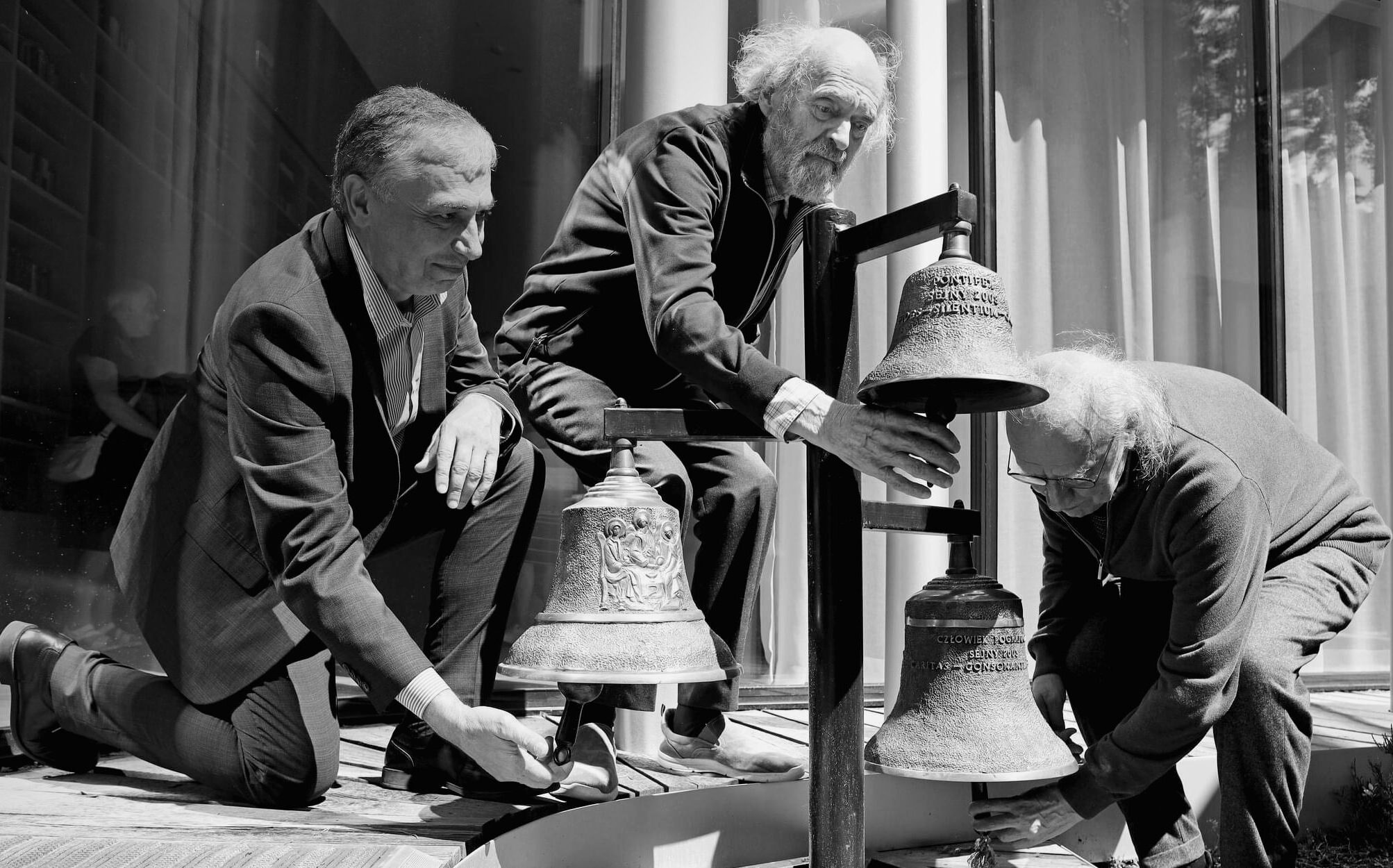 Photo en noir et blanc de Constantin Sigov aux côtés d’Arvo Pärt et de Valentin Silvestrov, au Centre Arvo Pärt. Ils manient des cloches.
