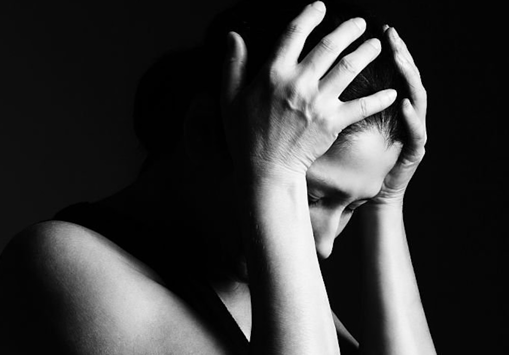 Femme se recueille sur un fond noir.