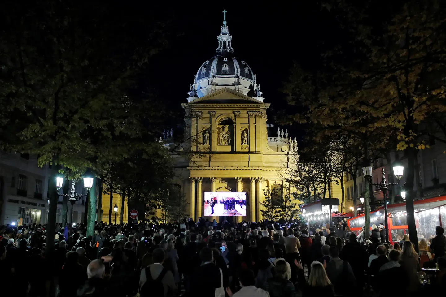 Une foule est rassemblée, la nuit, pour l'Hommage de la Nation à Samuel Paty, à la Sorbonne.