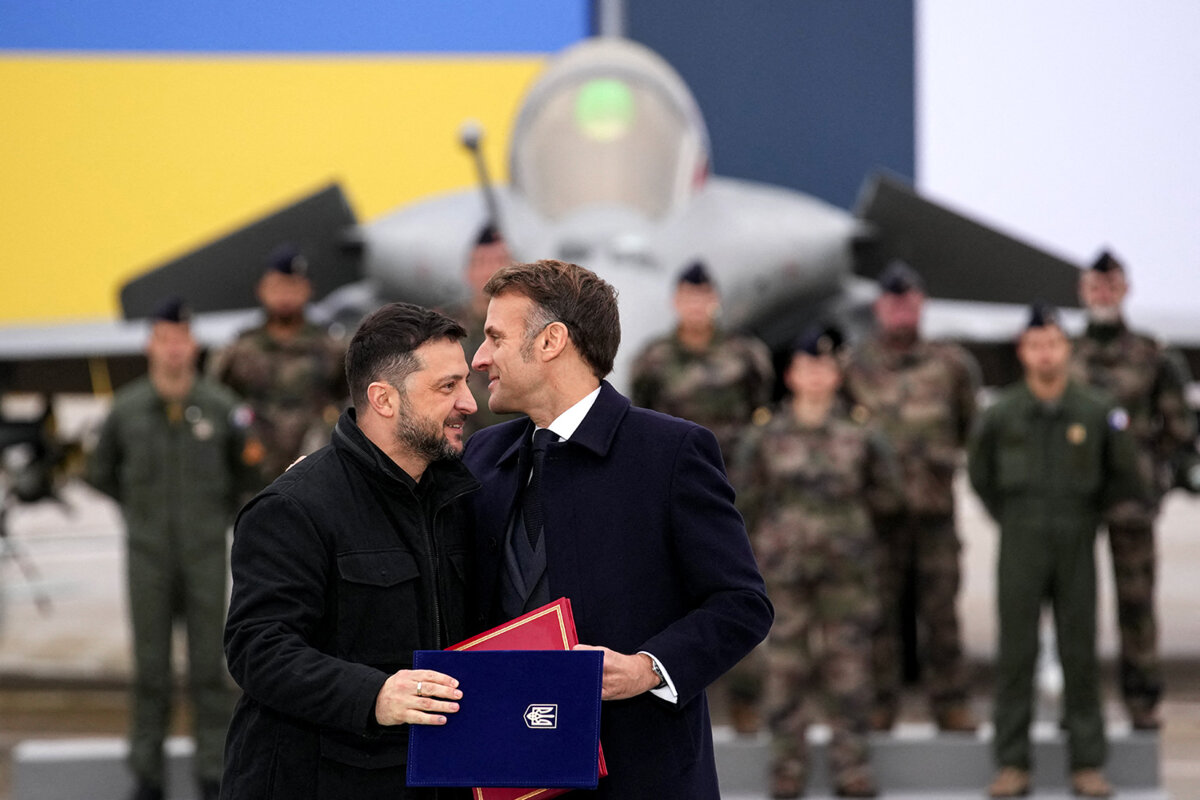 sur la base aérienne de Villacoublay (Yvelines) : Emmanuel Macron, président de la République française, aux côtés de Volodymyr Zelensky, son homologue ukrainien. Derrière eux on voit des militaires, un avion rafale et un drapeau ukrainien.