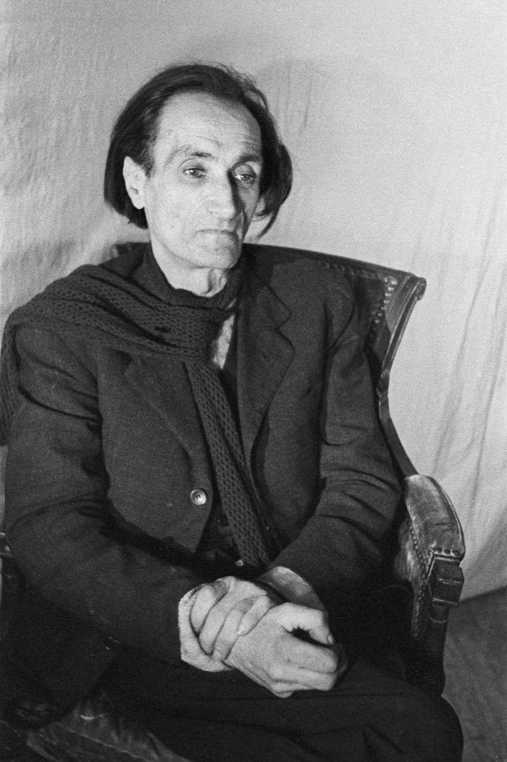 Portrait en noir et blanc d'Antonin Artaud assis dans un fauteuil devant un drap blanc.