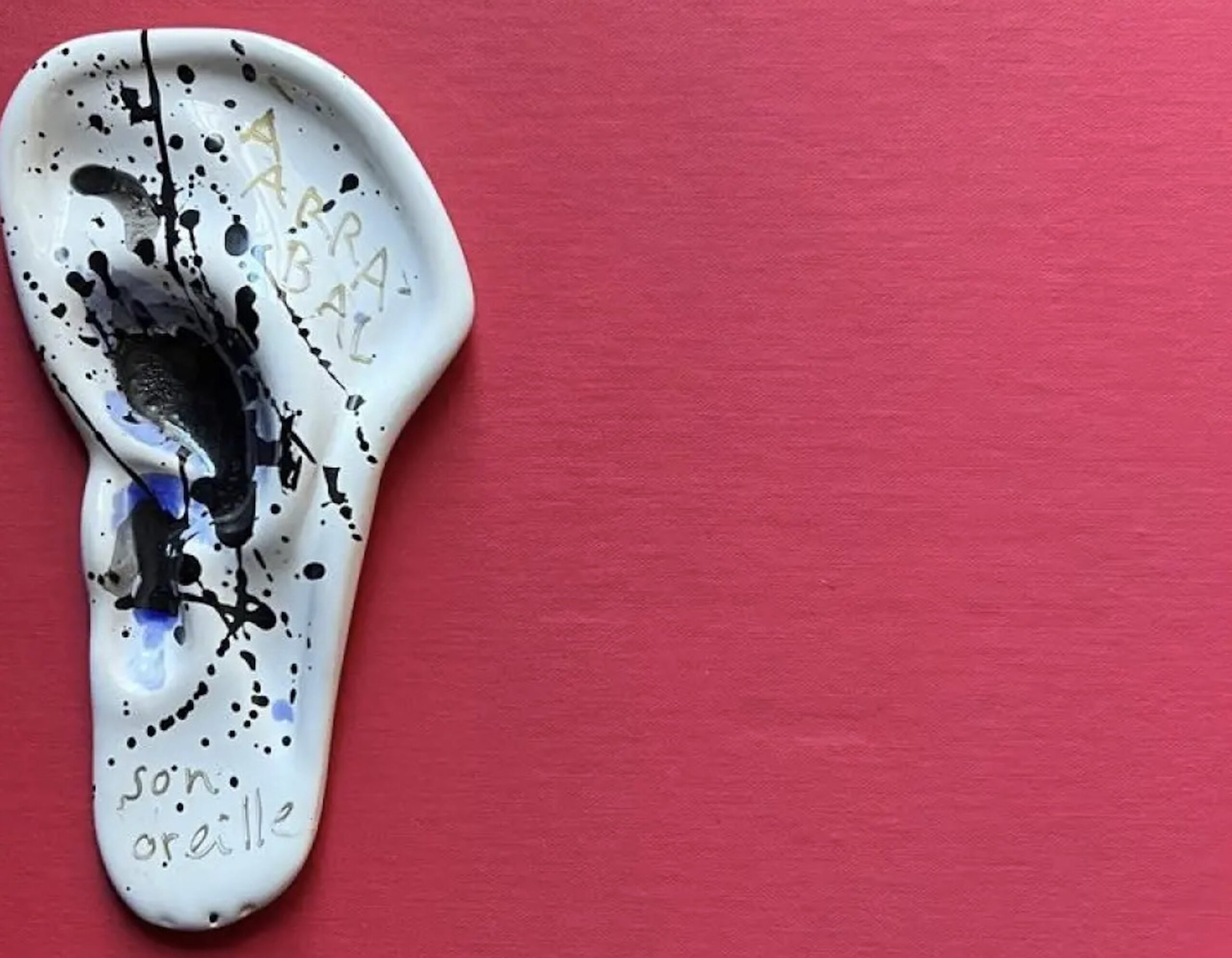 Oreille en céramique sur fond rouge.