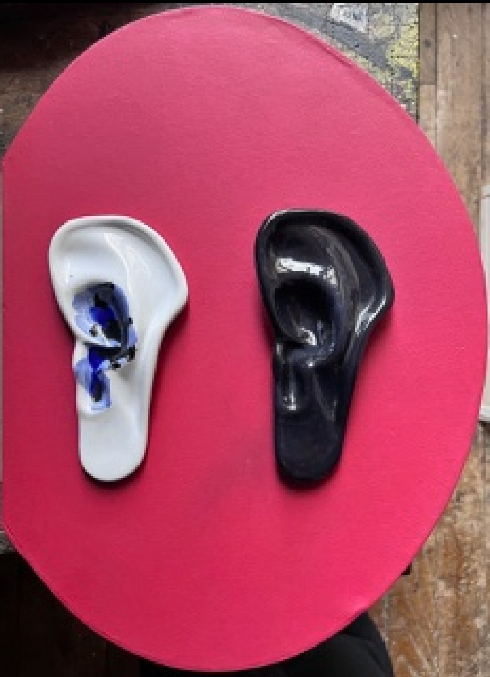 Un oreille blanche et un oreille noire en céramique sur fond rouge.