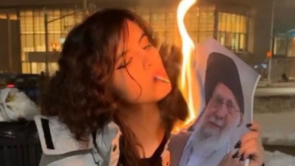 Une Iranienne allume une cigarette avec une photo en feu du guide suprême Ali Khamenei.