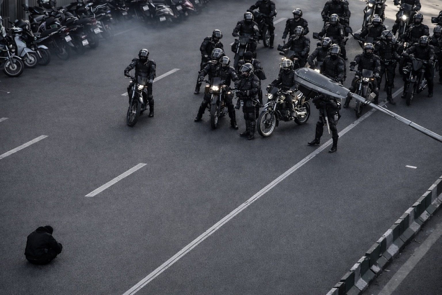 Un manifestant, seul, assis face aux milices du Guide suprême Ali Khamenei, dans une rue de Téhéran?