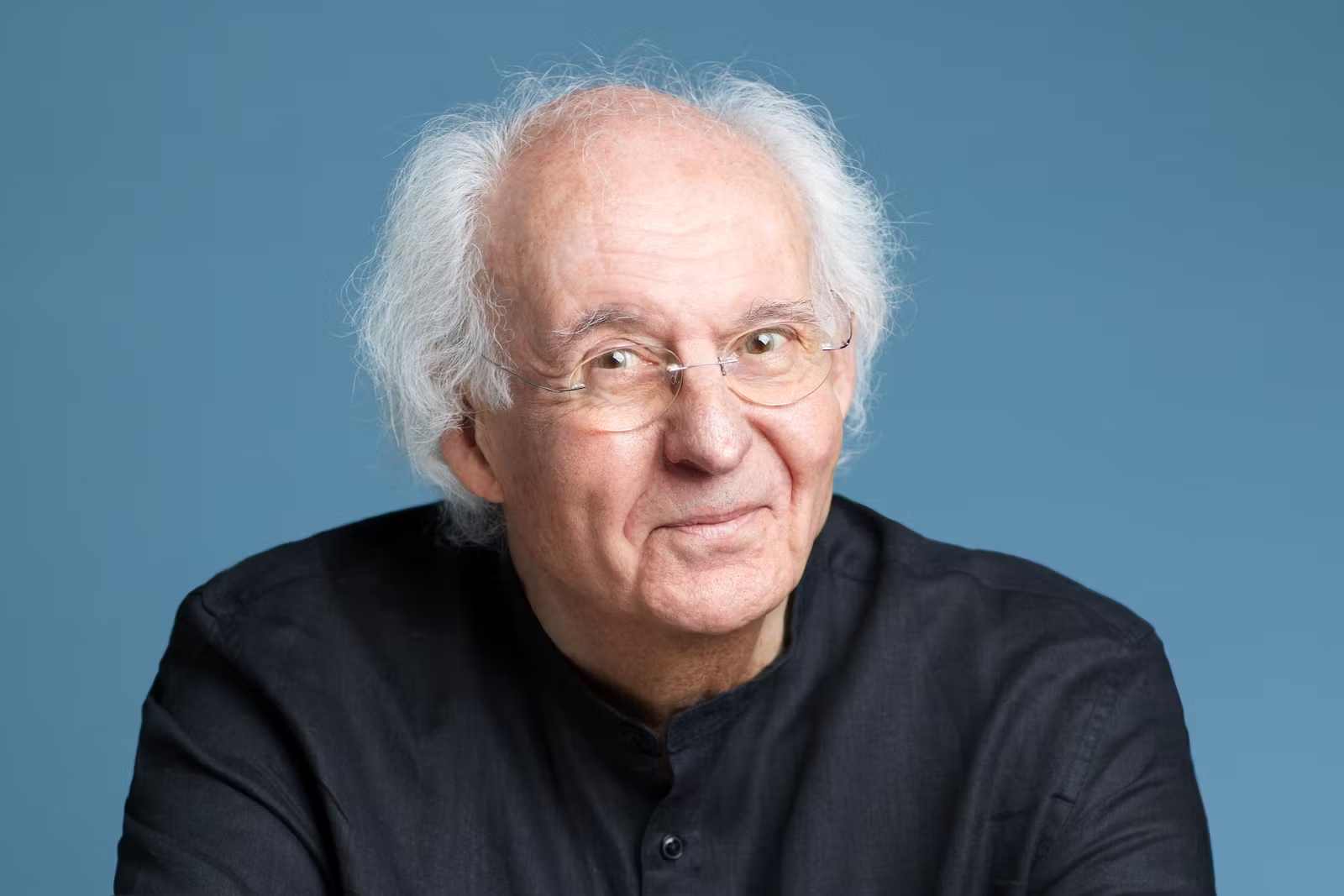 Portrait du philosophe Roger-Pol Droit devant un fond bleu.