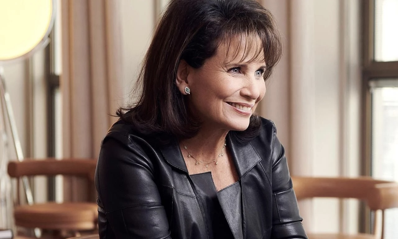 La journaliste et autrice Anne Sinclair assise dans un salon, avec le sourire.