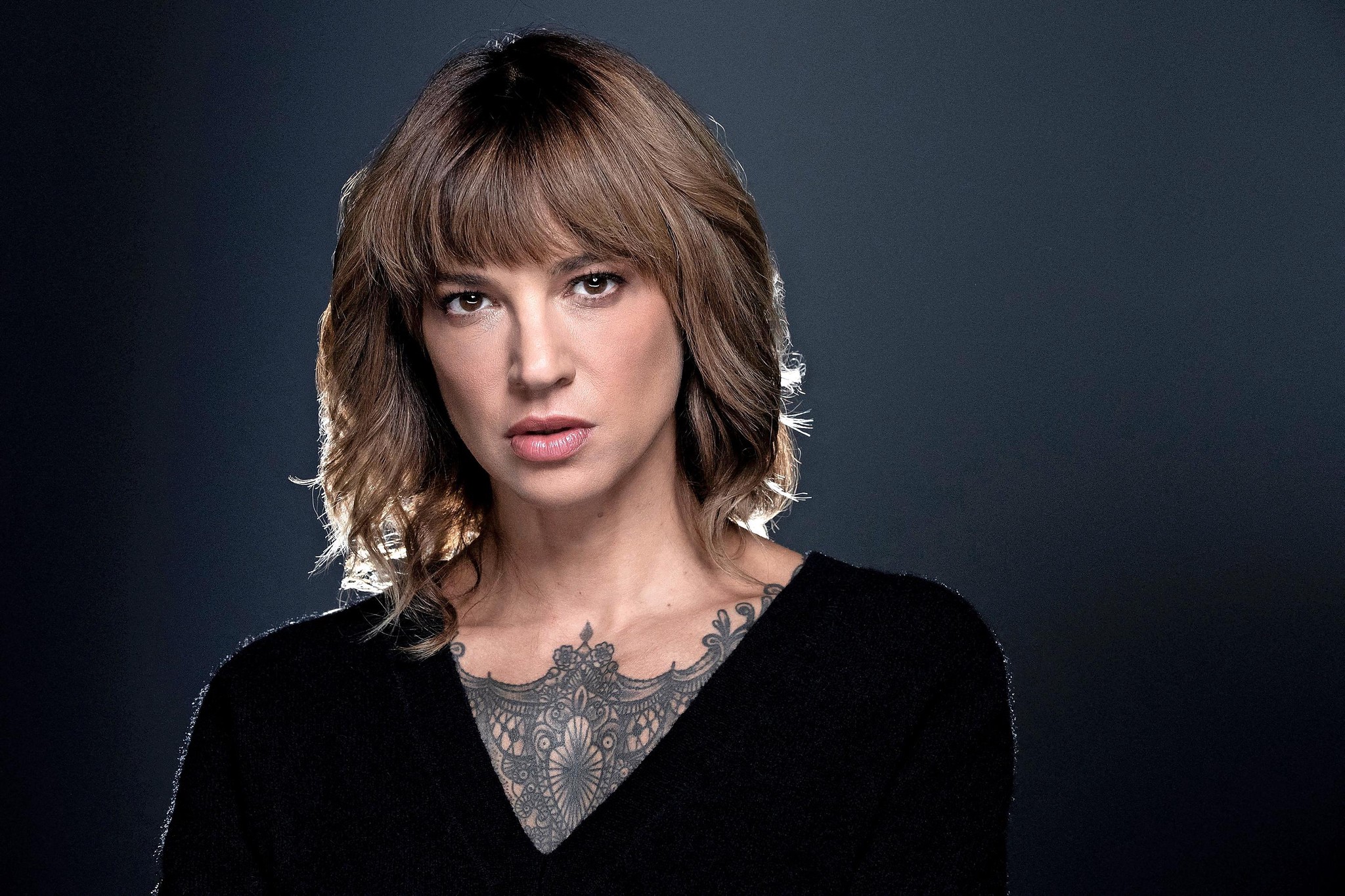 L’actrice, réalisatrice et chanteuse italienne, Asia Argento pose devant un fond unis gros foncé.