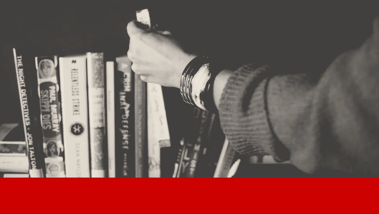 Une main de femme pioche un livre dans sa bibliothèque.