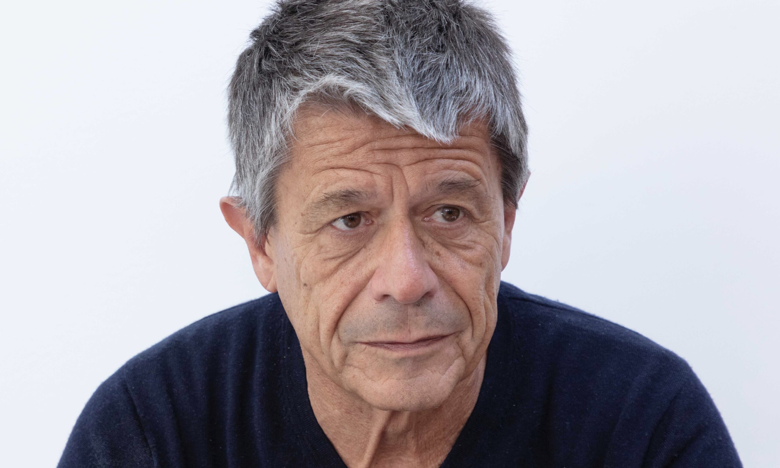 L’écrivain Emmanuel Carrère pose devant un fond blanc.
