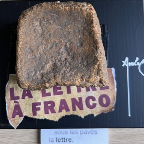 Poème plastique de Fernando Arrabal. On voit un pavé posé sur un carton où il est écrit « Lettre à Franco », titre d’un texte d’Arrabal.