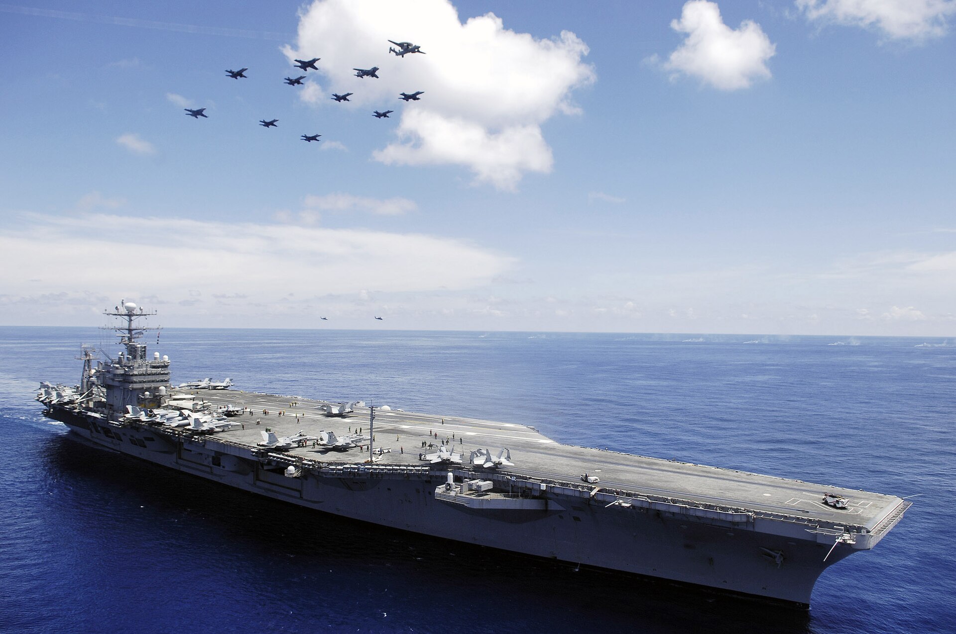 Photo du porte-avions USS Abraham Lincoln en mer, avec des avions qui le survole.