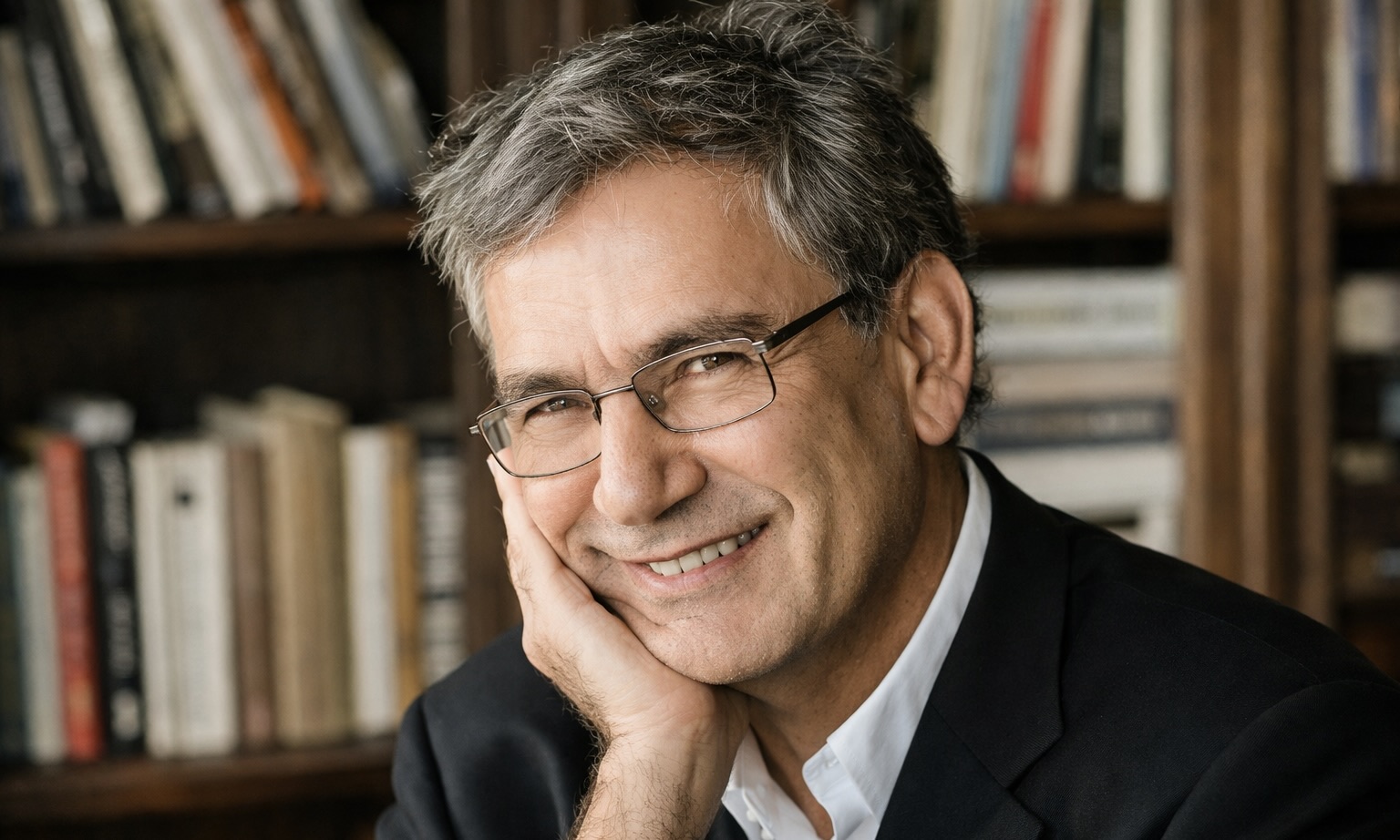 L'écrivain turc et prix Nobel de littérature Orhan Pamuk pose devant des étagères avec des livres. Il tient son visage avec sa main.