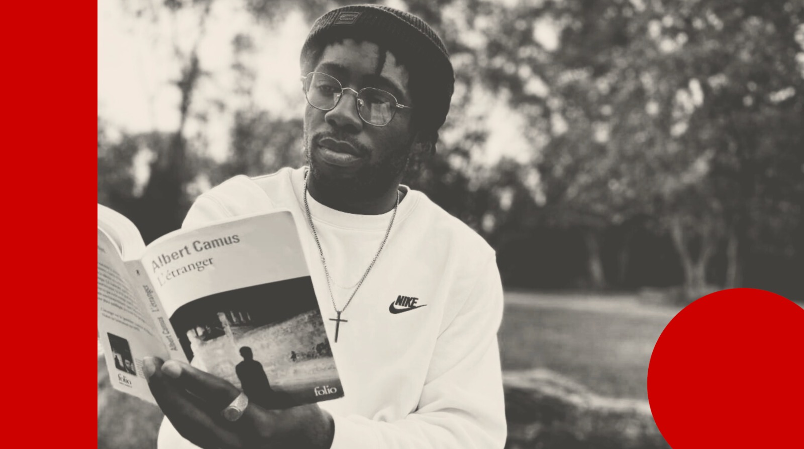 L'influenceur littéraire Ramsès Parent lit "L'Etranger" de Camus dans un parc.
