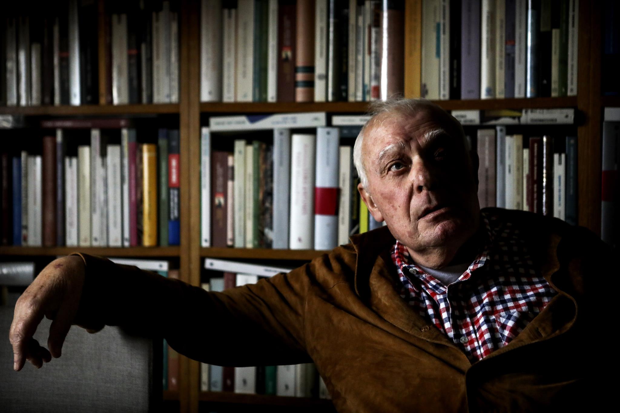António Lobo Antunes assis devant sa bibliothèque.