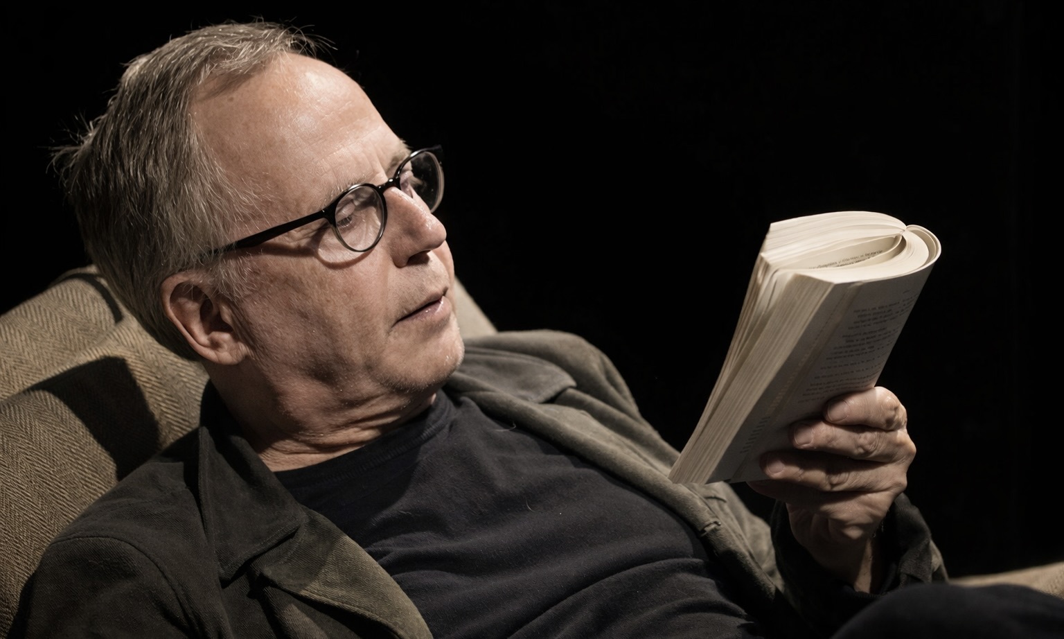 Le comédien français Fabrice Luchini, assis en train de lire.