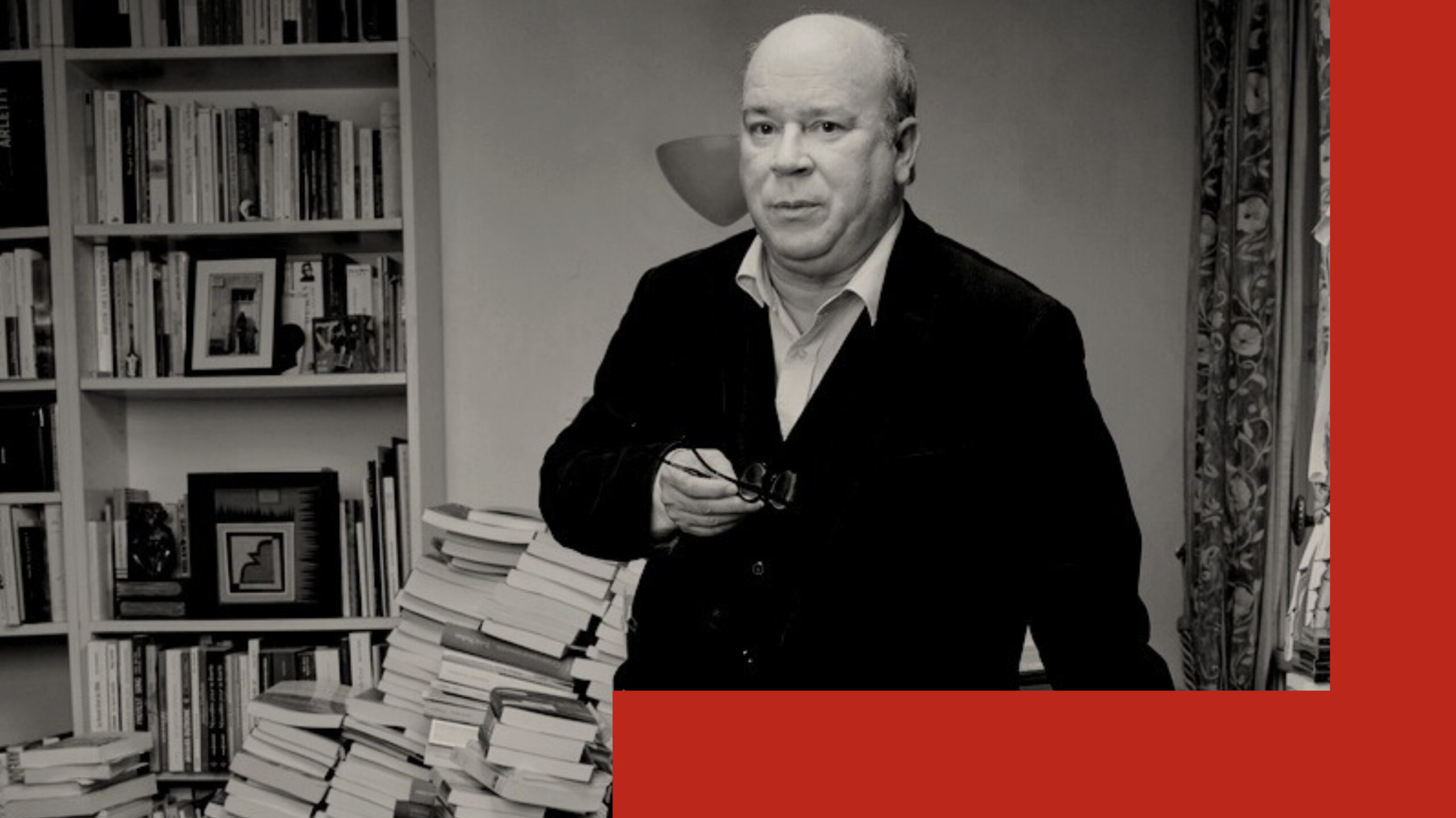 L’écrivain et académicien français, Marc Lambron, pose à côté d'une bibliothèque et d'une pile de livres.