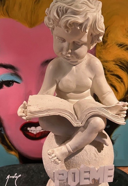 « Poème », collage de Fernando Arrabal. On voit une statuette d'angelot lire, derrière il y un portrait pop art de Marylin Monroe.