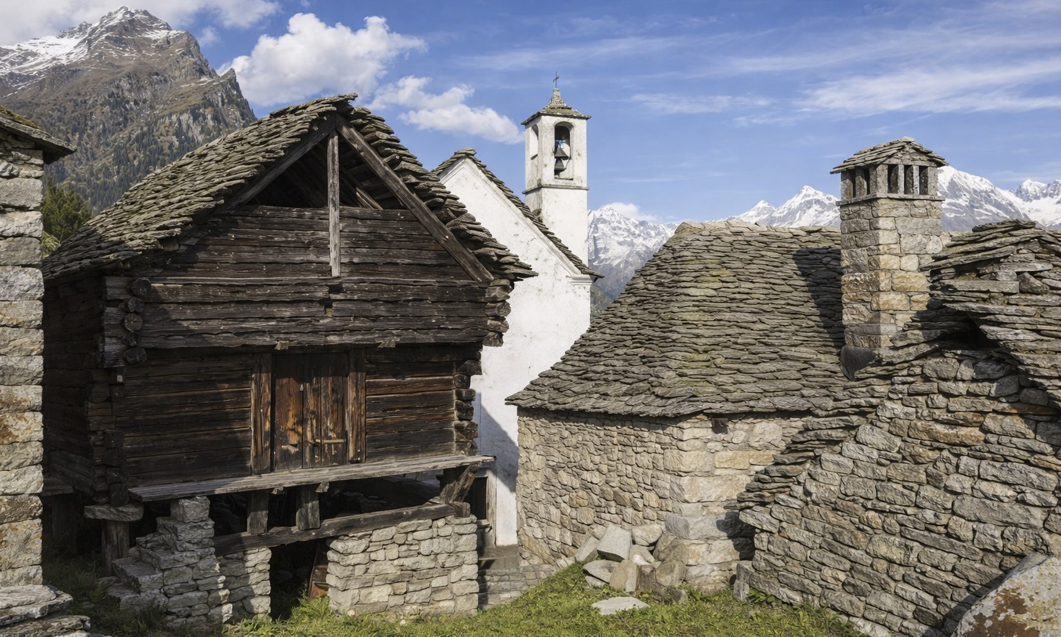 Le village Walser de Salecchio, on voit des maisons rudimentaires en bois et en pierre et un clocher d'aglise, dans un village perché sur les hauteurs des alpes italiennes.