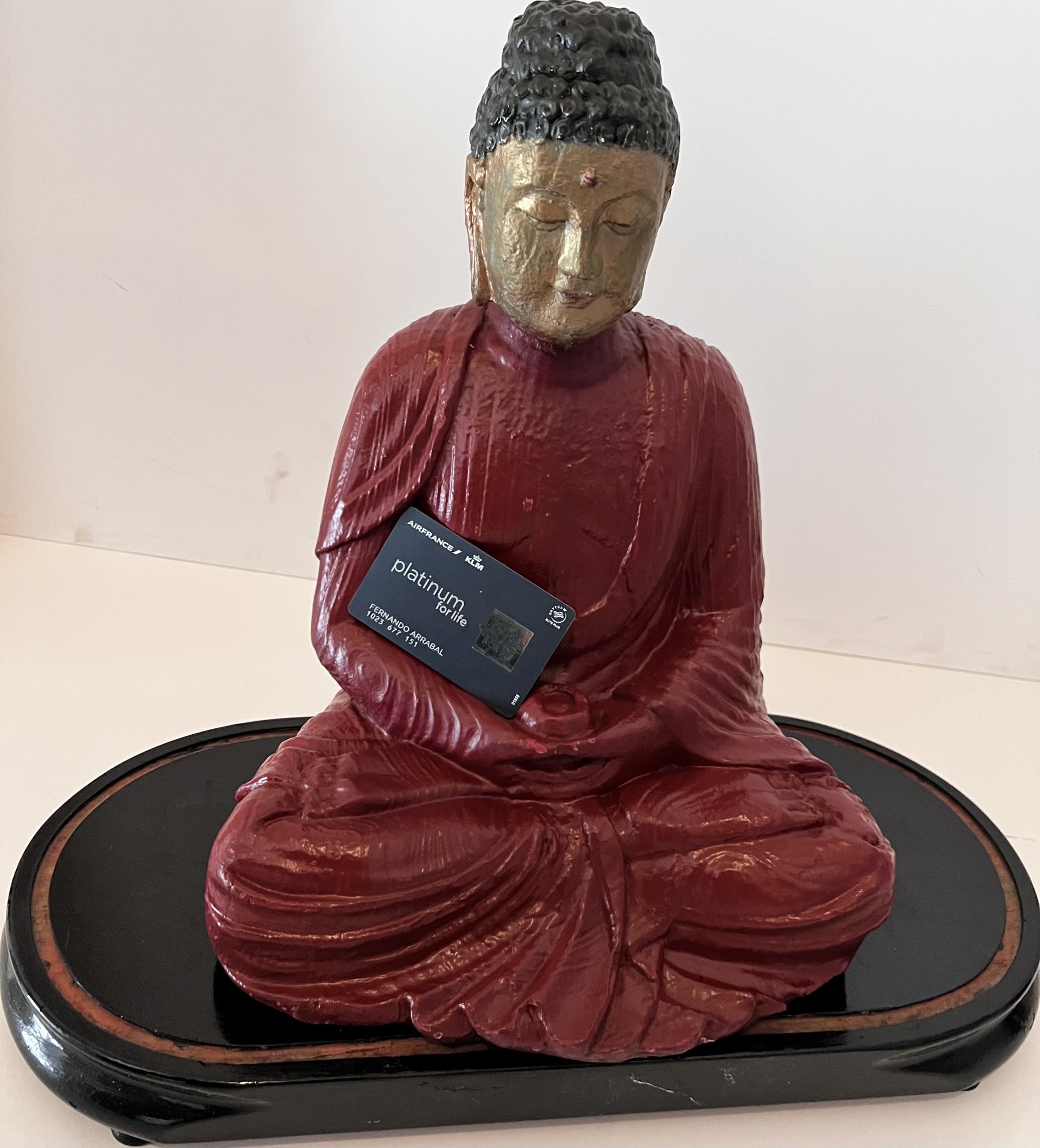 Poème plastique de Fernando Arrabal. Une statue de Bouddha rouge et or tient une carte noire Air France Platinium dans ses mains.